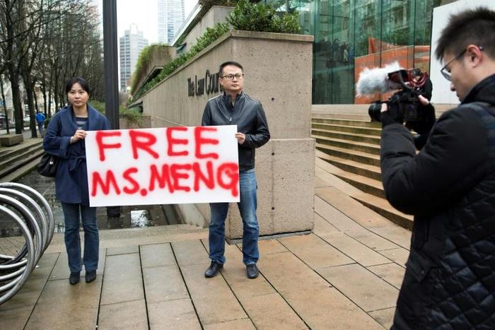 Two demonstrators outside a courthouse in Vancouver on December 10, 2018 call for the release of Huawei executive Meng Wanzhou after she was detained for possible extradition to the US for alleged sanctions busting