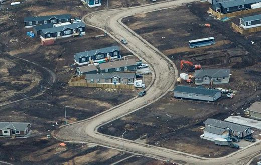 Aerial view of a residential neighborhood in Fort McMurray, Canada, where some homes have been rebuilt but many have not, one year after a massive forest fire