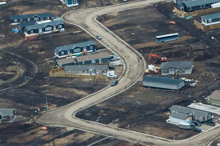 Aerial view of a residential neighborhood in Fort McMurray, Canada, where some homes have been rebuilt but many have not, one year after a massive forest fire