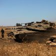 An Israeli soldier directs a Merkava tank stationed in the Israeli-annexed Golan Heights near the Quneitra crossing with Syria