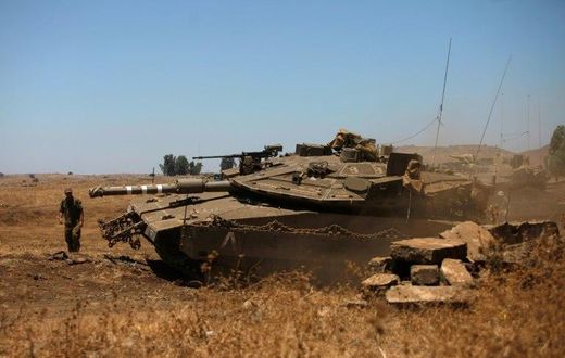 An Israeli soldier directs a Merkava tank stationed in the Israeli-annexed Golan Heights near the Quneitra crossing with Syria