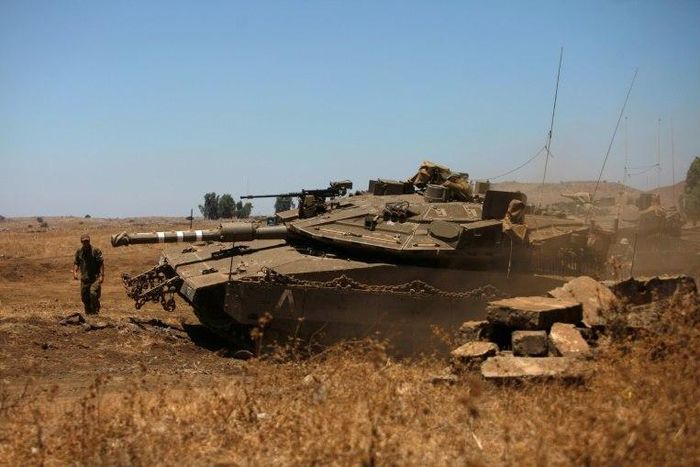 An Israeli soldier directs a Merkava tank stationed in the Israeli-annexed Golan Heights near the Quneitra crossing with Syria