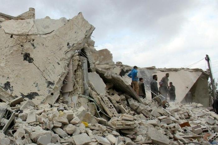 Civilians check destroyed buildings in the Syrian village of Kfar Jales, on the outskirts of Idlib, following air strikes by Syrian and Russian warplanes