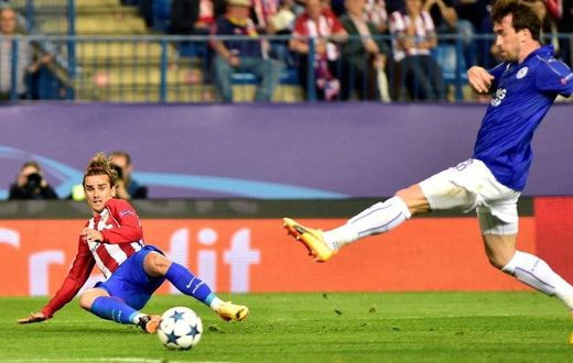 Atletico Madrid forward Antoine Griezmann (L) curls a cross in past Leicester City defender Christian Fuchs during the Champions League quarter-final first leg at the Vicente Calderon stadium in Madrid on April 12, 2017