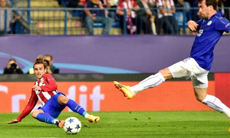 Atletico Madrid forward Antoine Griezmann (L) curls a cross in past Leicester City defender Christian Fuchs during the Champions League quarter-final first leg at the Vicente Calderon stadium in Madrid on April 12, 2017