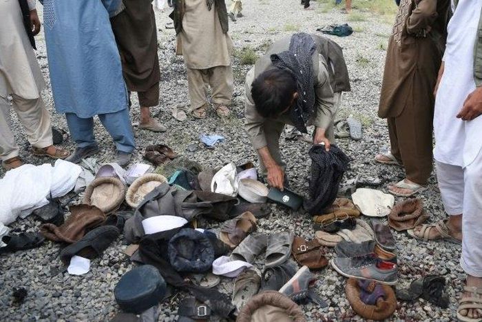 Afghan men examine the belongings of blast victims at the site of a series of explosions that targeted a funeral of a politician's son, who was killed during an anti-government protest a day earlier in Kabul
