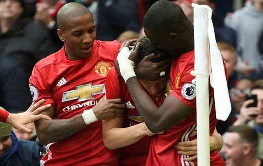 Manchester United's midfielder Ashley Young (L) and defender Eric Bailly (R) congratulate midfielder Ander Herrera (C) after Herrera scored their second goal during the English Premier League football match against Chelsea April 16, 2017