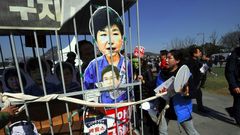Anti-government activists carry a mock jail containing a cardboard cut-out of South Korea's President Park Geun-Hye of Park in Seoul on March 10, 2017 after the Constitutional Court upheld her impeachment