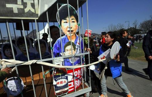Anti-government activists carry a mock jail containing a cardboard cut-out of South Korea's President Park Geun-Hye of Park in Seoul on March 10, 2017 after the Constitutional Court upheld her impeachment