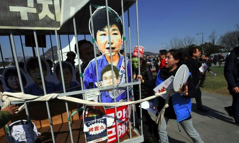 Anti-government activists carry a mock jail containing a cardboard cut-out of South Korea's President Park Geun-Hye of Park in Seoul on March 10, 2017 after the Constitutional Court upheld her impeachment