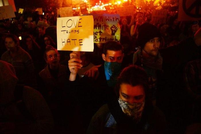 A demonstrator holds up a placard during a protest against Donald Trump's US presidential election victory at City Hall in Portland, Oregon on November 11, 2016