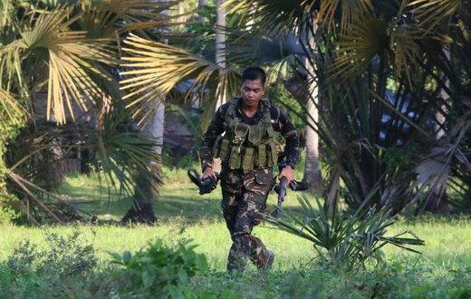 A soldiers runs after retrieving the rifle of a colleague after clashes with militants on Bohol island
