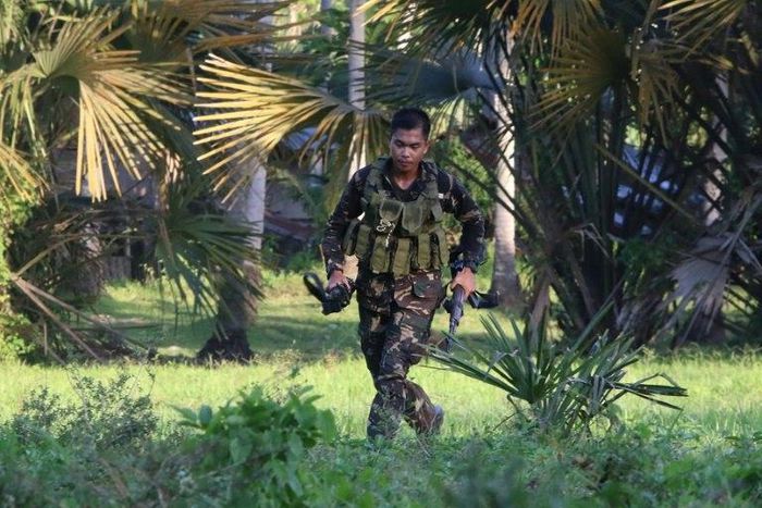 A soldiers runs after retrieving the rifle of a colleague after clashes with militants on Bohol island