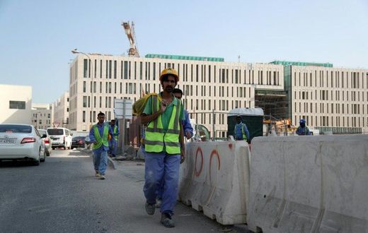 Migrant workers are seen walking next to a construction site in the Qatari capital Doha on December 6, 2016