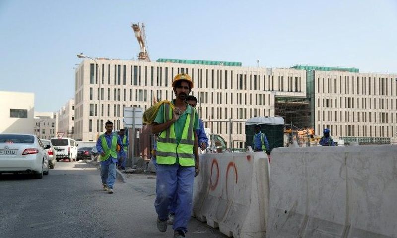 Migrant workers are seen walking next to a construction site in the Qatari capital Doha on December 6, 2016
