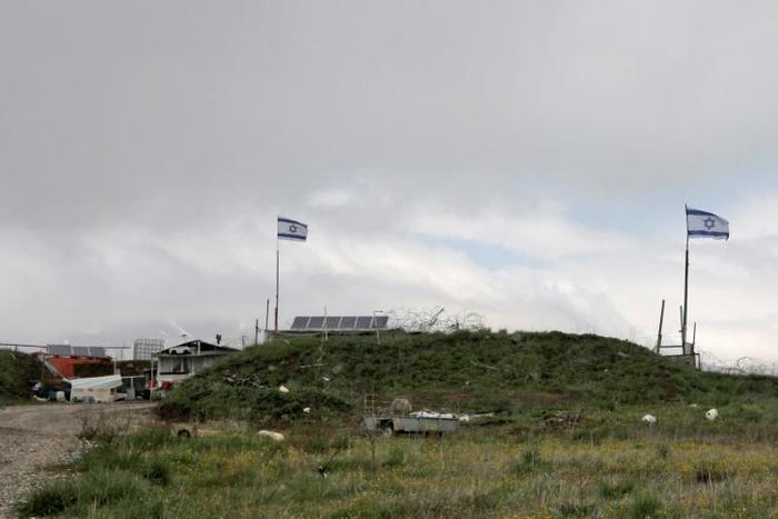 Israeli flags fly over a military base near the border fence with Syria in the Israeli-annexed Golan Heights, south of the Druze village of Majdal Shams