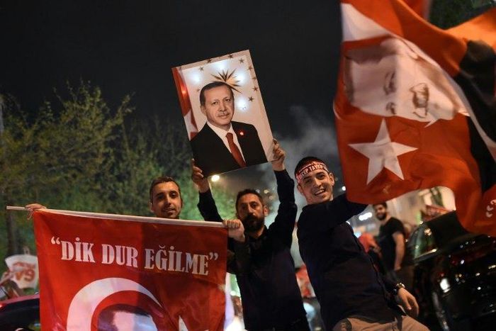 A supporter of the "Yes" campaign holds up a picture of Turkish president Recep Tayyip Erdogan during a rally near the headquarters of the conservative Justice and Development Party (AKP) in Istanbul on April 16, 2017 after initial results