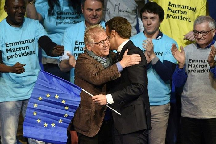 Emmanuel Macron clasps a EU flag as he hugs famous MEP Daniel Cohn-Bendit (L)