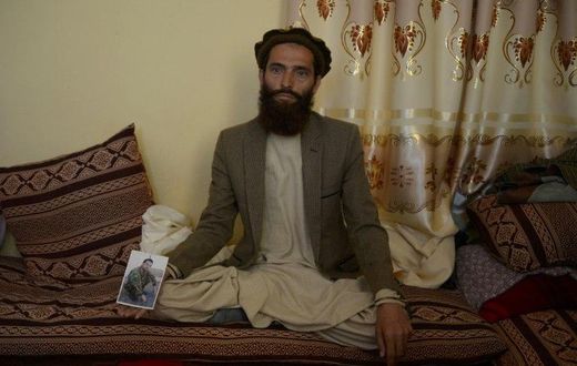 Afghan resident Ahmadullah poses for a photograph on April 24, 2017 with a picture of his brother Shir Mohammad, a soldier killed in a Taliban attack on an army base on the outskirts of Mazar-i- Sharif