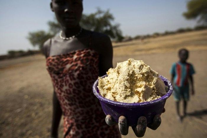 A woman holds out a bowl of partially boiled maize in Ngop in South Sudan's Unity State on March 10, 2017