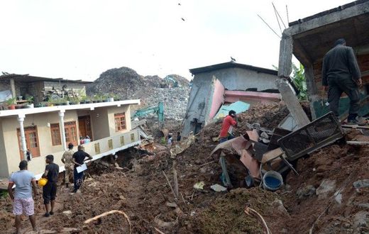 Residents and rescuers check damaged homes at the site of a collapsed garbage dump near Colombo, on April 15, 2017