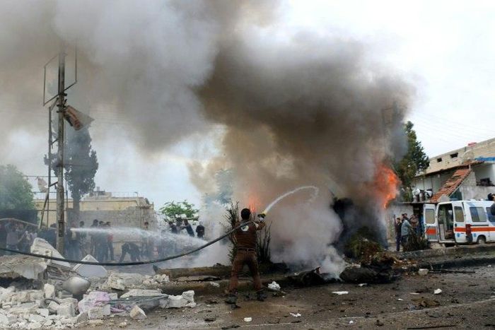 A member of the Syrian civil defence tries to extinguish fire from a burning vehicle following a reported car bomb explosion in the rebel-held town of Azaz in northern Syria on May 3, 2017