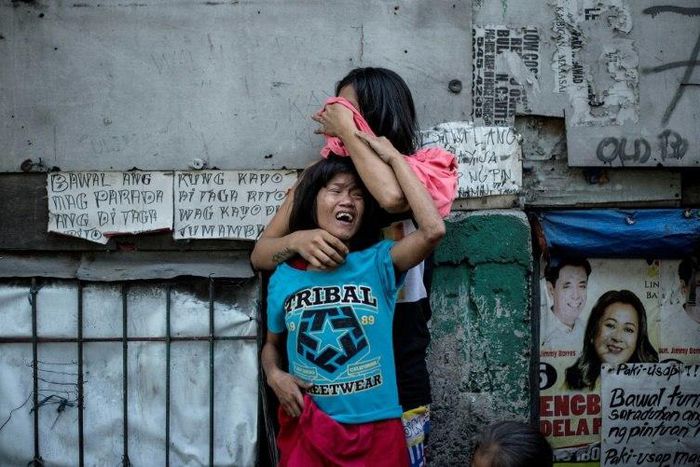 Two Filipinos mourn the death of a relative, a suspected drug dealer gunned down by unidentified assailants in Manila earlier in March as part of President Duterte's deadly drug war