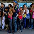 People queue to buy basic food and household items outside a supermarket in Caracas, on September 28, 2016