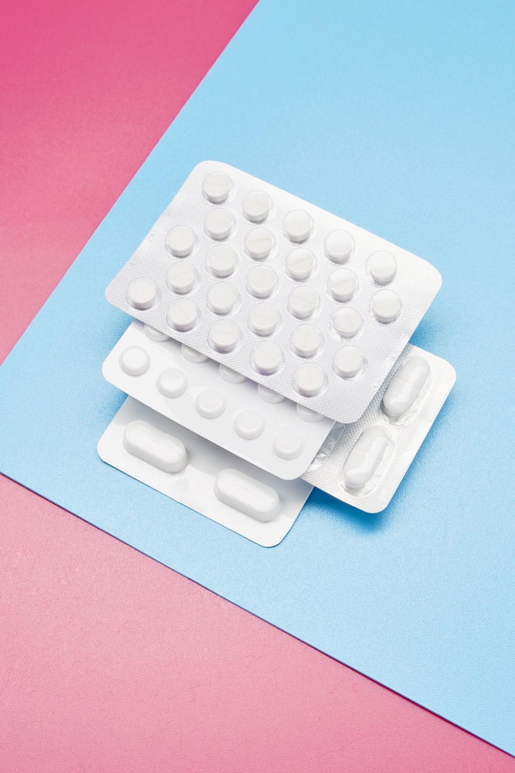 White blister packs with pills on blue and pink background