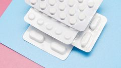 White blister packs with pills on blue and pink background