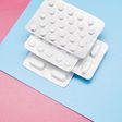 White blister packs with pills on blue and pink background