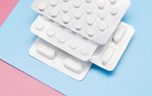 White blister packs with pills on blue and pink background