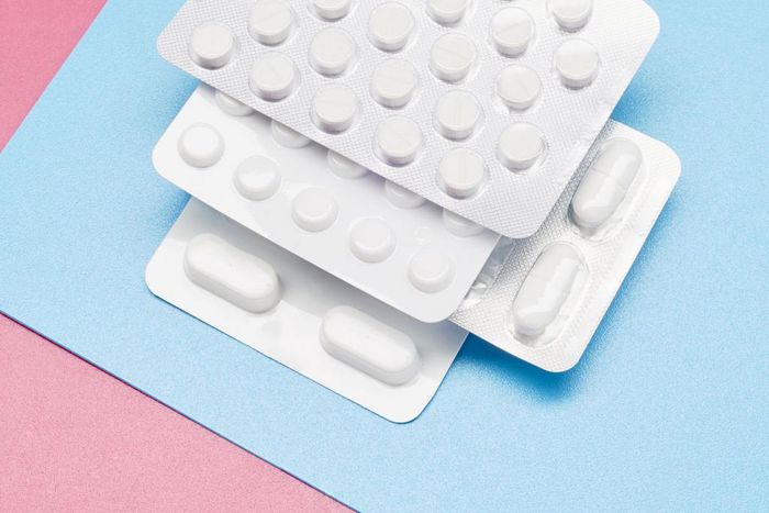 White blister packs with pills on blue and pink background