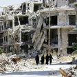 Women walk between destroyed buildings in the government-held Jouret al-Shiah neighbourhood of the central Syrian city of Homs