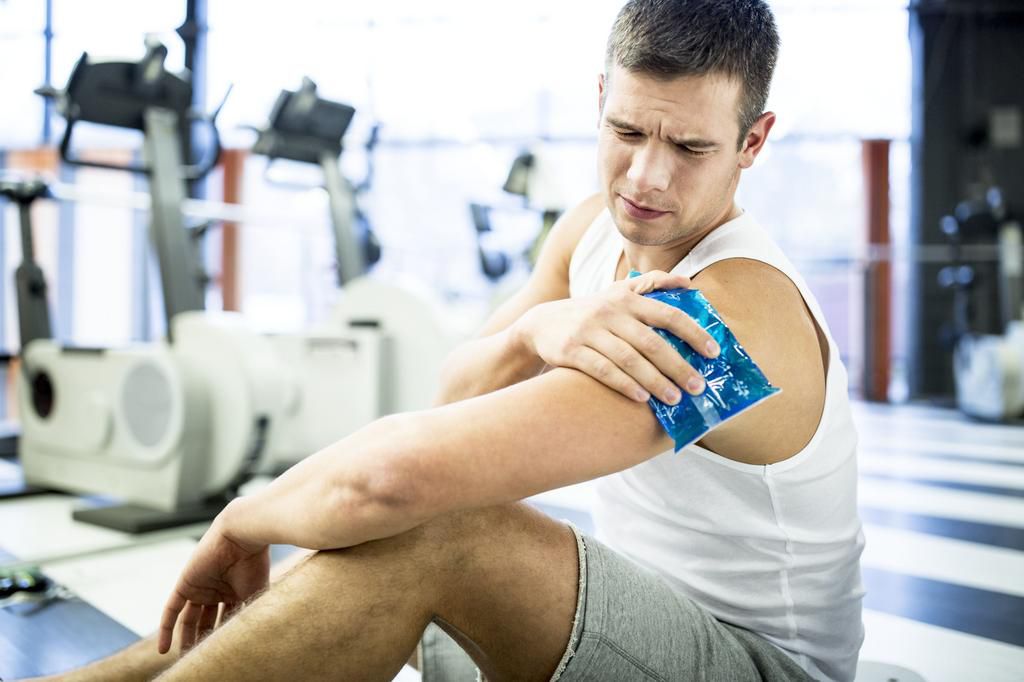Young man holding ice pack on shoulder