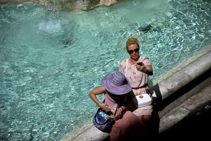 Tourists takes selfies by the Trevi Fountain in Rome
