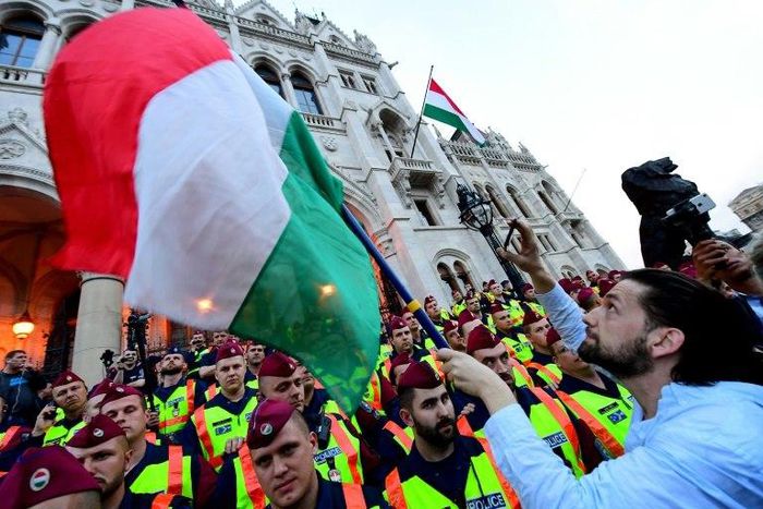 People protest as police officers stand guard in front of the parliament building in Budapest on April 4, 2017