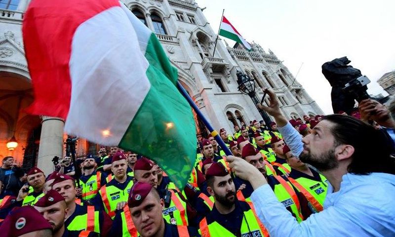 People protest as police officers stand guard in front of the parliament building in Budapest on April 4, 2017