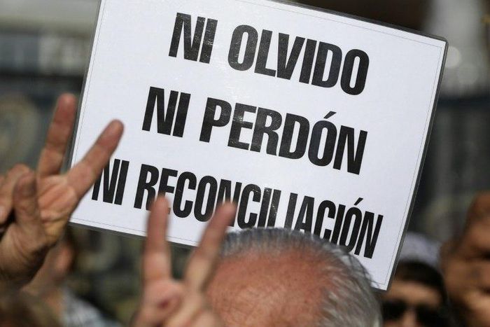 A demonstrator holds a sign reading in Spanish "Neither forget nor forgive, nor reconciliation", during the Madres de Plaza de Mayo human rights group's weekly demonstration at the Plaza de Mayo square in Buenos Aires on May 4, 2017