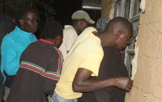 Residents of Nakuru Town West peep through the window of a house where a woman was killed by her lover.