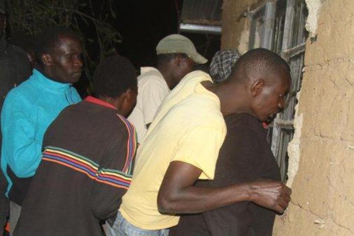 Residents of Nakuru Town West peep through the window of a house where a woman was killed by her lover.