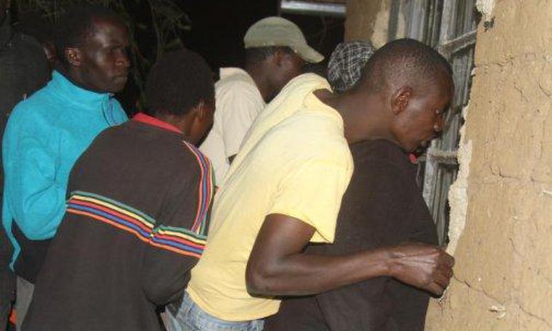 Residents of Nakuru Town West peep through the window of a house where a woman was killed by her lover.
