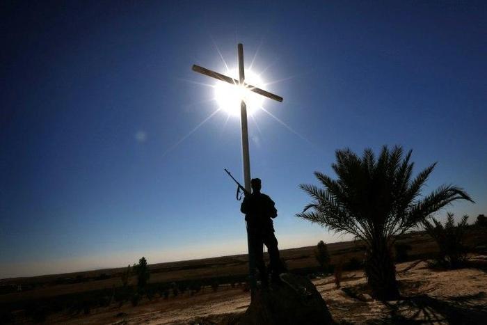A member of the Iraqi Christian forces Kataeb Babylon (Babylon Brigades) stands guard beneath a cross at the Mar Behnam Syriac Catholic monastery in Khidr Ilyas