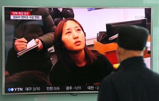 People at a railway station in Seoul look at a news report on the arrest of Chung Yoo-Ra (C), the 20-year-old daughter of the woman dubbed South Korea's "Rasputin"