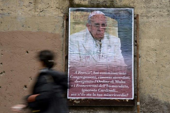 A woman walks past an anti-Pope Francis poster featuring a portrait of the pontiff and a critical message ending "Where's your mercy?" in central Rome on February 6, 2017