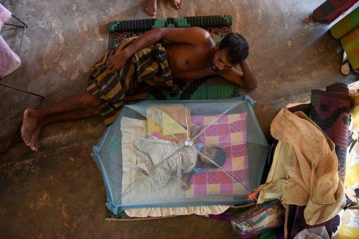 A Sri Lankan child and man rest at a relief camp after being evacuated following flooding Sri Lanka that killed more than 200 people