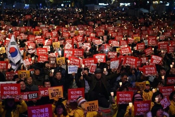 Protesters hold candles and banners calling for the resignation of South Korea's President Park Geun-Hye during an anti-government rally in central Seoul on November 19, 2016