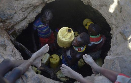A young girl passes up a jerrycan filled with murky water trickling into a waterhole from underground rocks near Lokitaung in northern Kenya's Turkana county