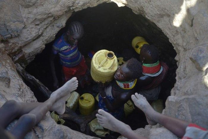 A young girl passes up a jerrycan filled with murky water trickling into a waterhole from underground rocks near Lokitaung in northern Kenya's Turkana county