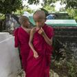Cemetery personnel bury the body of a three-year-old child, one of three victims of an exorcism ritual in Twante, south of Yangon on October 22, 2016, as young novice monks looks on